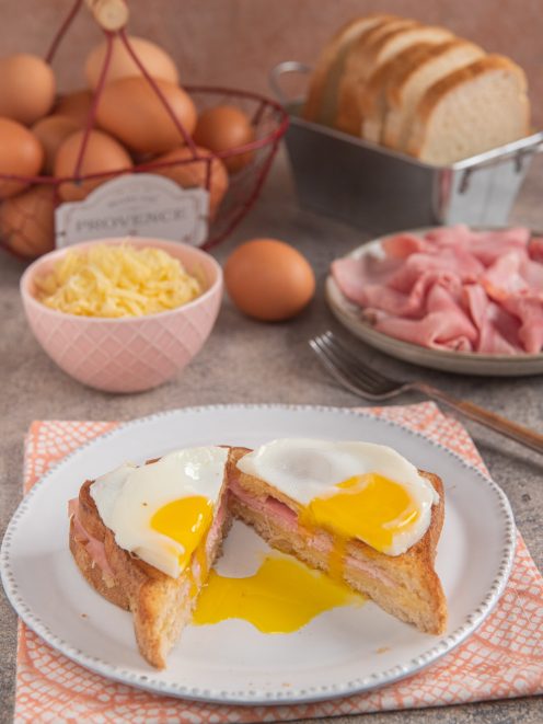 Croque Madame tagliato a metà con tuorlo colante, prosciutto cotto e pane tostato