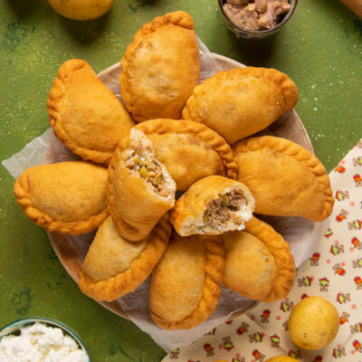 Mini panzerotti con tonno, ricotta e patate fritti e dorati, uno aperto a mostrare il ripieno
