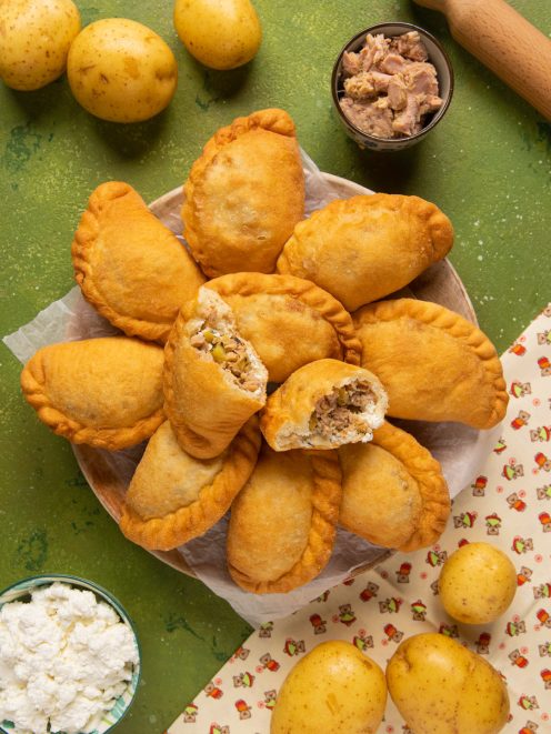 Mini panzerotti con tonno, ricotta e patate fritti e dorati, uno aperto a mostrare il ripieno