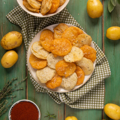 Patate fritte in pastella con paprika, sale grosso e rametti di erbe aromatiche fresche