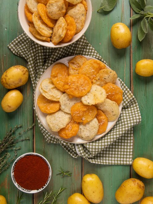 Patate fritte in pastella con paprika, sale grosso e rametti di erbe aromatiche fresche