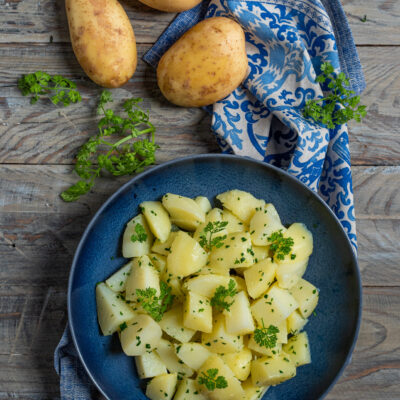 Patate lesse a pezzi condite con prezzemolo fresco tritato e a foglie intere