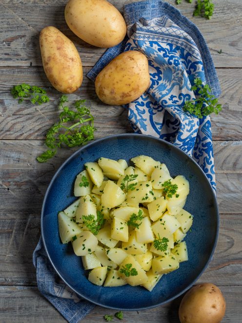 Patate lesse a pezzi condite con prezzemolo fresco tritato e a foglie intere