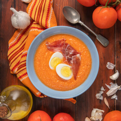 Salmorejo cremoso di pomodoro guarnito con uovo sodo a fette e prosciutto crudo