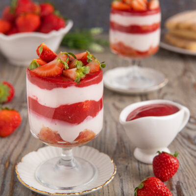 Tiramisù allo yogurt con fragole servito in coppa a strati con fragole fresche e coulis