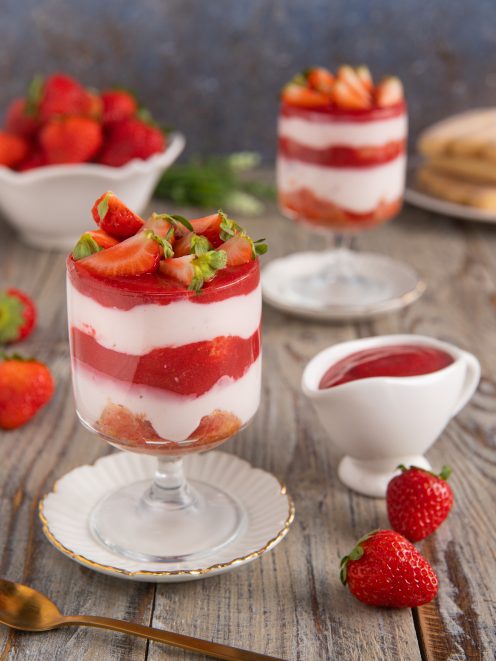 Tiramisù allo yogurt con fragole servito in coppa a strati con fragole fresche e coulis