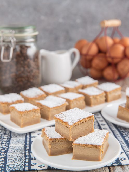 Torta magica al caffè tagliata a quadrotti con crema morbida e zucchero a velo in superficie