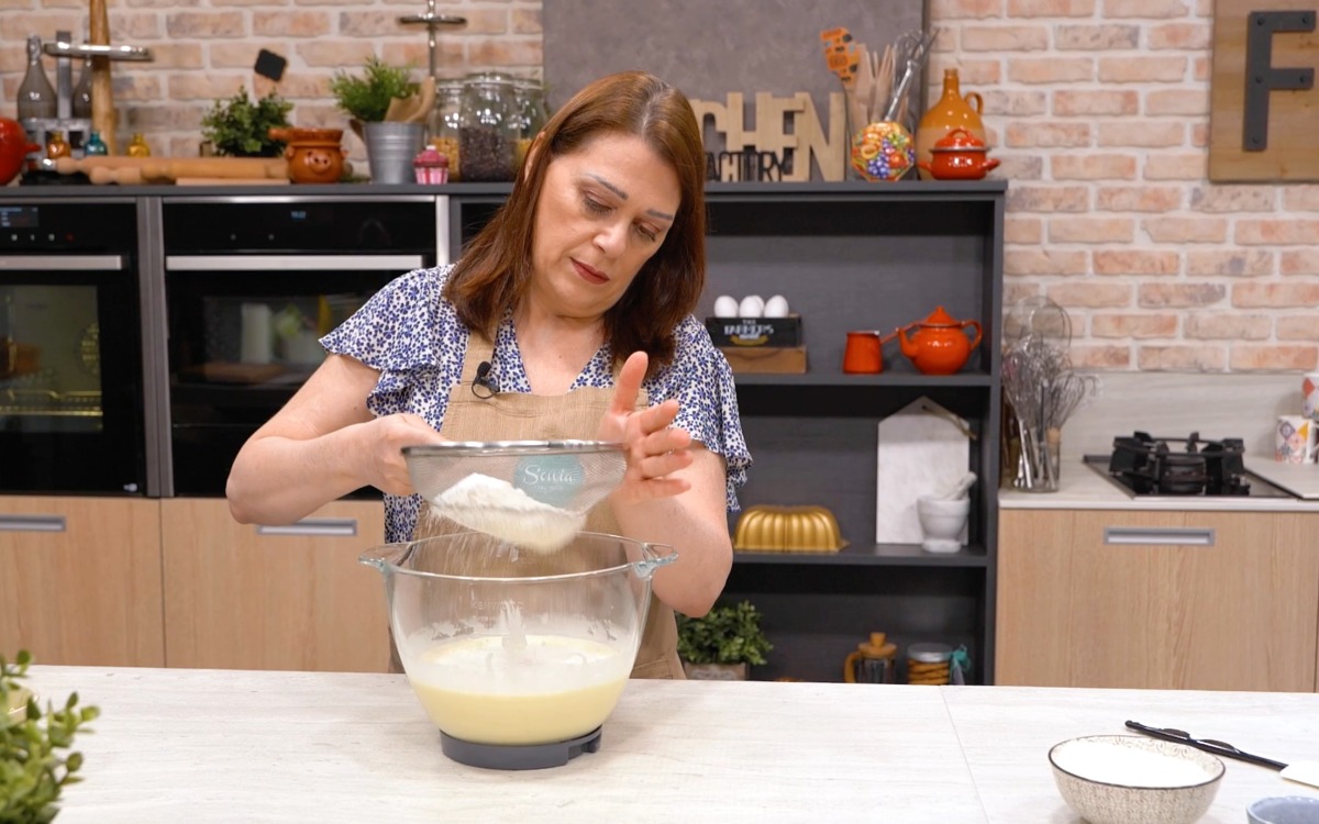 Farina setacciata versata nel composto montato per la torta al cocco
