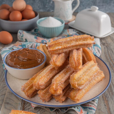 Churros fritti ricoperti di zucchero serviti con salsa al caramello per intingere