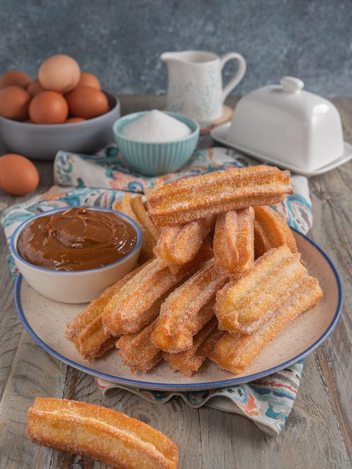 Churros fritti ricoperti di zucchero serviti con salsa al caramello per intingere