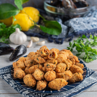 Cozze fritte impanate con prezzemolo, dorate e croccanti, servite in abbondanza