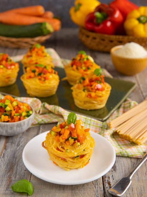 Cupcake di spaghetti nido con dadolata di peperoni, zucchine e carote e foglia di basilico