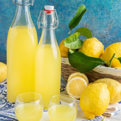 Limoncello fatto in casa in due bottiglie con limoni freschi con foglie accanto