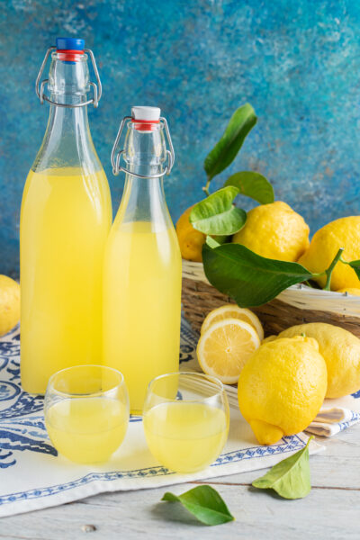Limoncello fatto in casa in due bottiglie con limoni freschi con foglie accanto