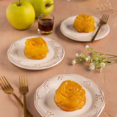 Mini tarte tatin di mele a forma di rosa caramellata servite su piccoli piatti individuali