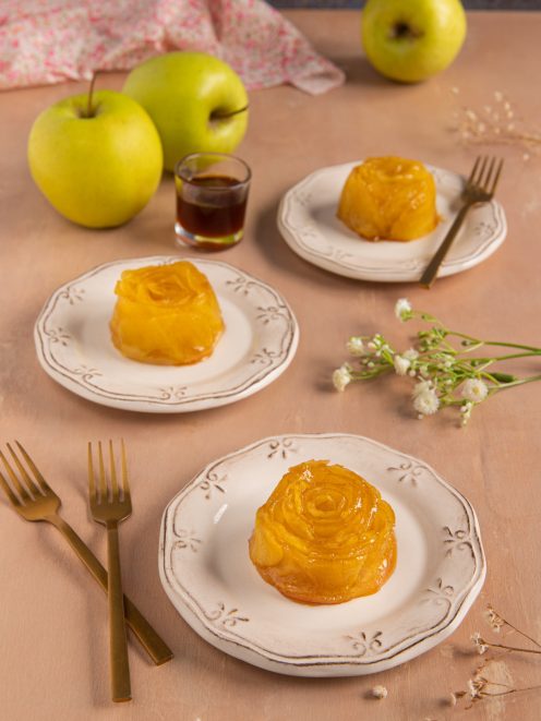 Mini tarte tatin di mele a forma di rosa caramellata servite su piccoli piatti individuali