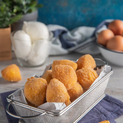Mozzarelline fritte dorate servite in cestino, con una aperta che rivela il cuore filante