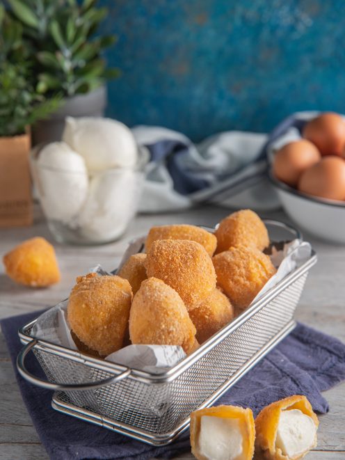 Mozzarelline fritte dorate servite in cestino, con una aperta che rivela il cuore filante