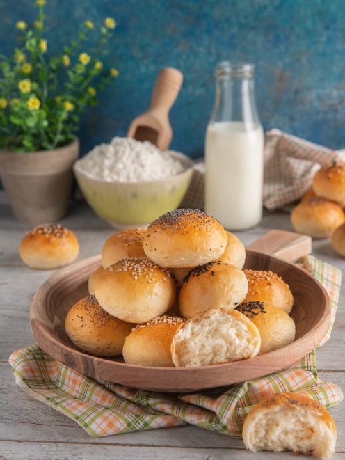 Panini al latte soffici impilati, alcuni con semi di sesamo e papavero, uno spezzato a metà