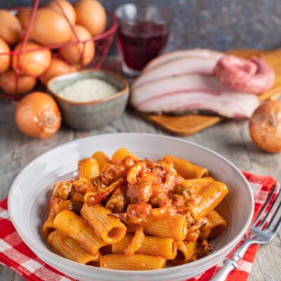 Pasta alla zozzona con rigatoni conditi da un ricco sugo di pomodoro, salsiccia e guanciale