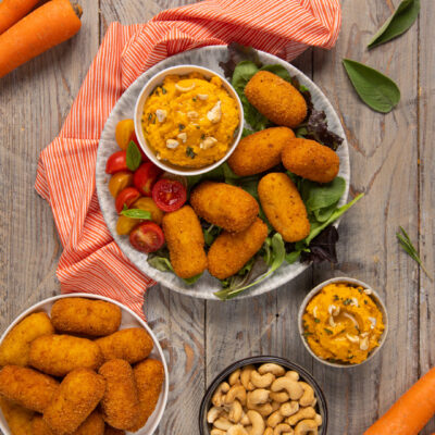 Polpette di baccalà fritte servite su insalata mista con hummus di carote e anacardi