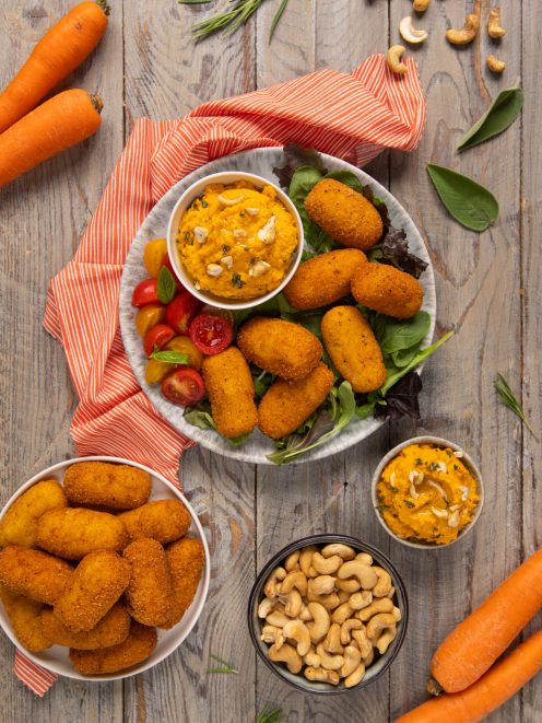 Polpette di baccalà fritte servite su insalata mista con hummus di carote e anacardi