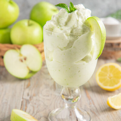 Sorbetto alla mela verde servito in coppa con fetta di mela e foglioline di menta