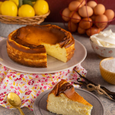 Cheesecake basca con superficie caramellata e fetta tagliata dal cuore cremoso