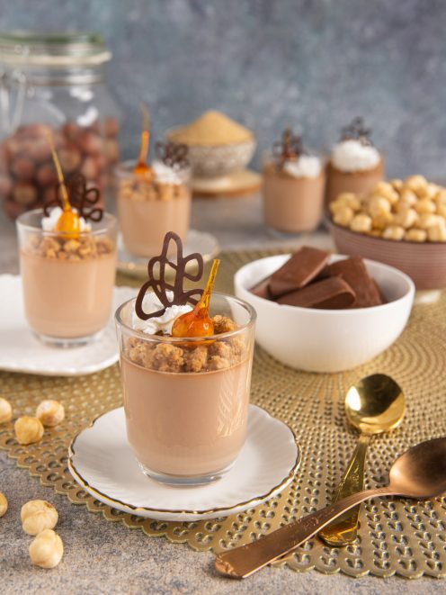 Cremoso ai gianduiotti servito in bicchiere con crumble alle nocciole, decorazione di cioccolato e caramello
