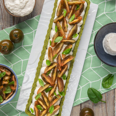 Crostata salata con base verde agli spinaci, stracciatella e fette di pomodoro kumato con basilico