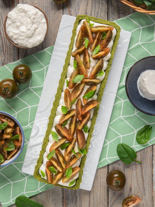 Crostata salata con base verde agli spinaci, stracciatella e fette di pomodoro kumato con basilico