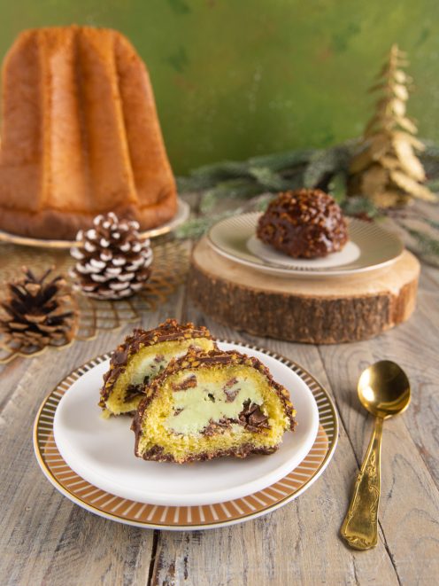 Delizie al pandoro e pistacchio a fette, ricoperte di cioccolato e granella, con crema verde al centro