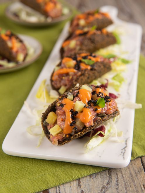 Mini tacos di tartare di scamone alla panzanella con patate al burro champagne, salsa piccante e caviale su letto di insalata