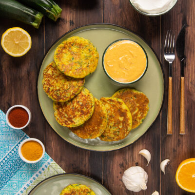 Pancake di zucchine dorati serviti con salsa allo yogurt alla curcuma e paprika