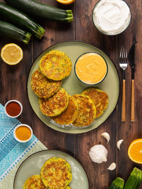 Pancake di zucchine dorati serviti con salsa allo yogurt alla curcuma e paprika