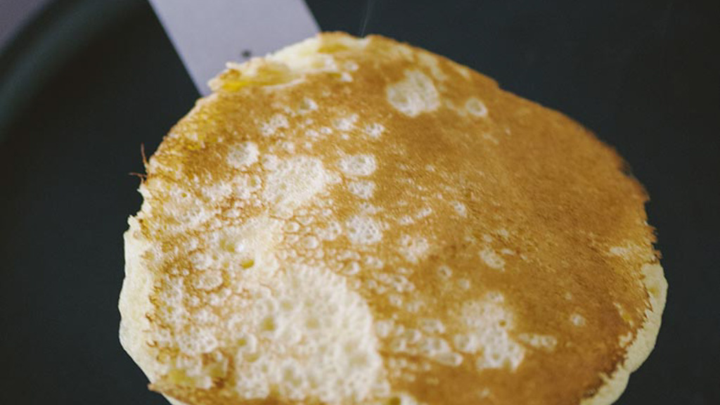 Pancake girato con la paletta mentre il secondo lato si dora in padella