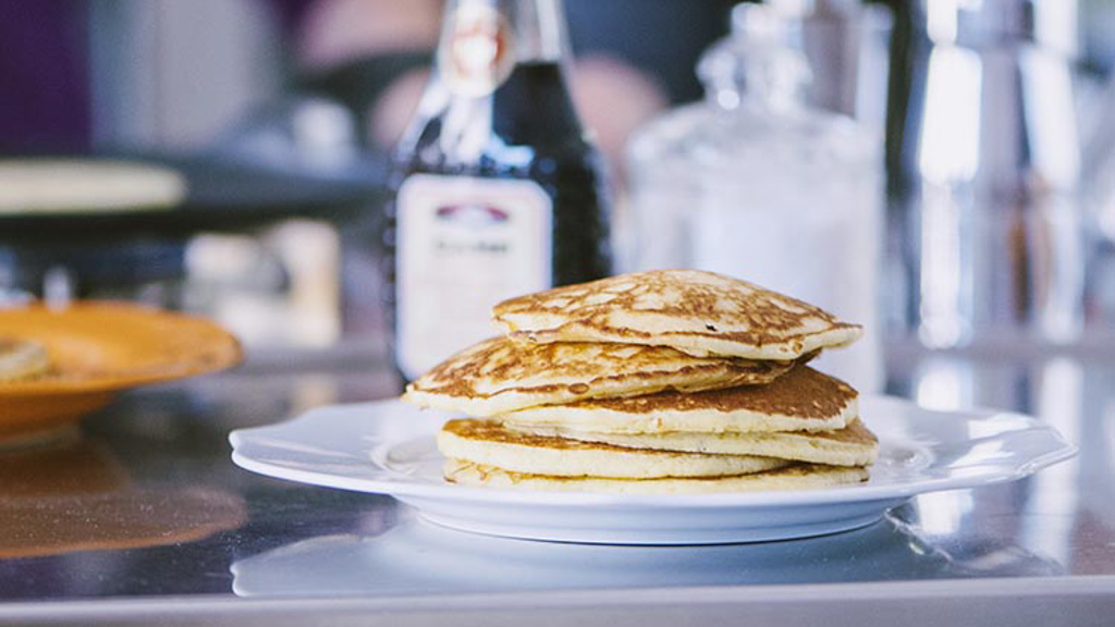 Pancakes impilati su un piatto con sciroppo d'acero versato sopra