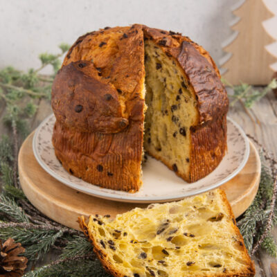 Panettone con gocce di cioccolato tagliato, con una fetta appoggiata davanti che mostra l'alveolatura