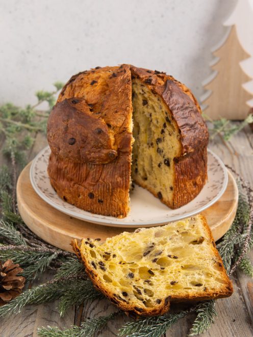 Panettone con gocce di cioccolato tagliato, con una fetta appoggiata davanti che mostra l'alveolatura