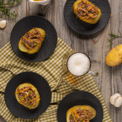 Patate ripiene di stinco sfilacciato con salsa alla birra ed erba cipollina, servite in quattro porzioni