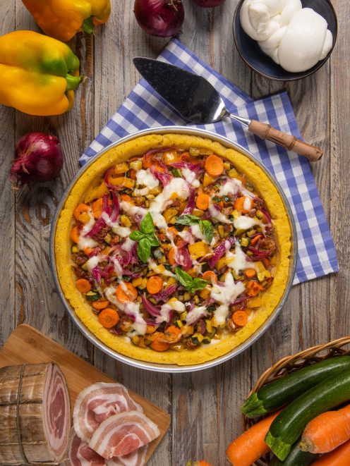 Pizza di polenta con verdure grigliate, mozzarella filante e basilico fresco, servita in teglia