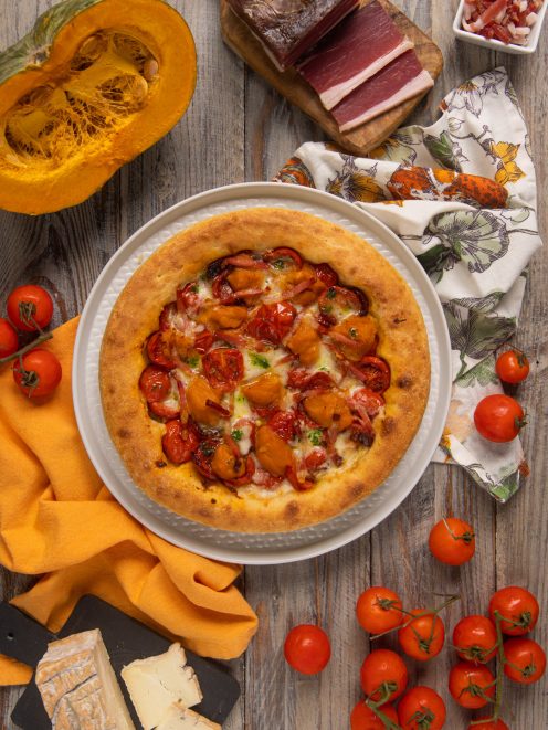 Pizza gourmet con crosta alta, cubetti di zucca, pomodorini confit e speck croccante
