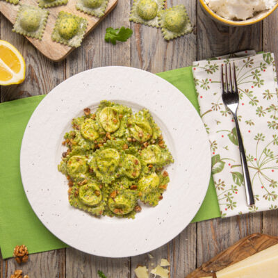 Ravioli alla rucola con pecorino conditi al burro e noci tritate, serviti su piatto