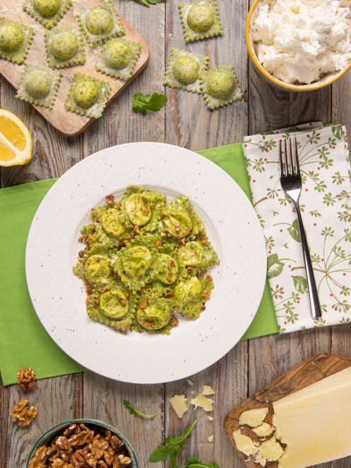 Ravioli alla rucola con pecorino conditi al burro e noci tritate, serviti su piatto