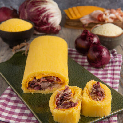 Rotolo di polenta con bacon, radicchio e cheddar affettato che rivela il ripieno colorato