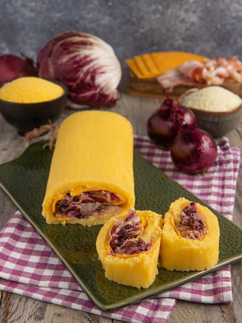 Rotolo di polenta con bacon, radicchio e cheddar affettato che rivela il ripieno colorato