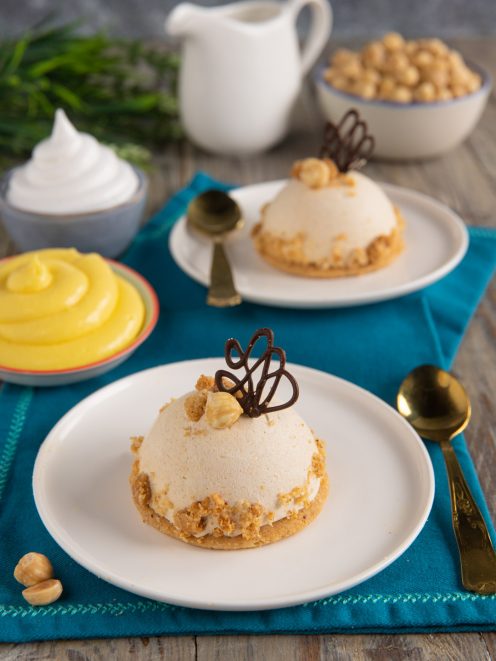 Semifreddo alla nocciola a cupola su base croccante, decorato con nocciole e ricciolo di cioccolato