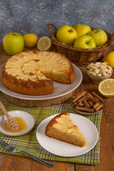 Torta di mele senza glutine con fettine disposte a ventaglio e una fetta servita accanto