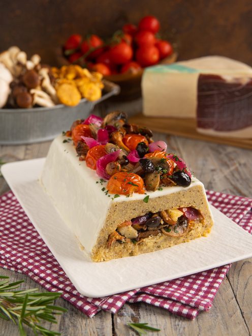 Tronchetto di polenta taragna farcito con funghi trifolati, guarnito da pomodorini e cipolla rossa