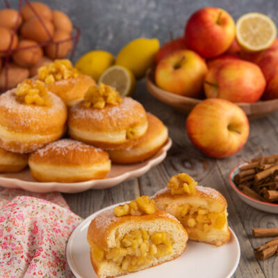 Bomboloni alle mele caramellate tagliati a meta con ripieno abbondante e superficie zuccherata